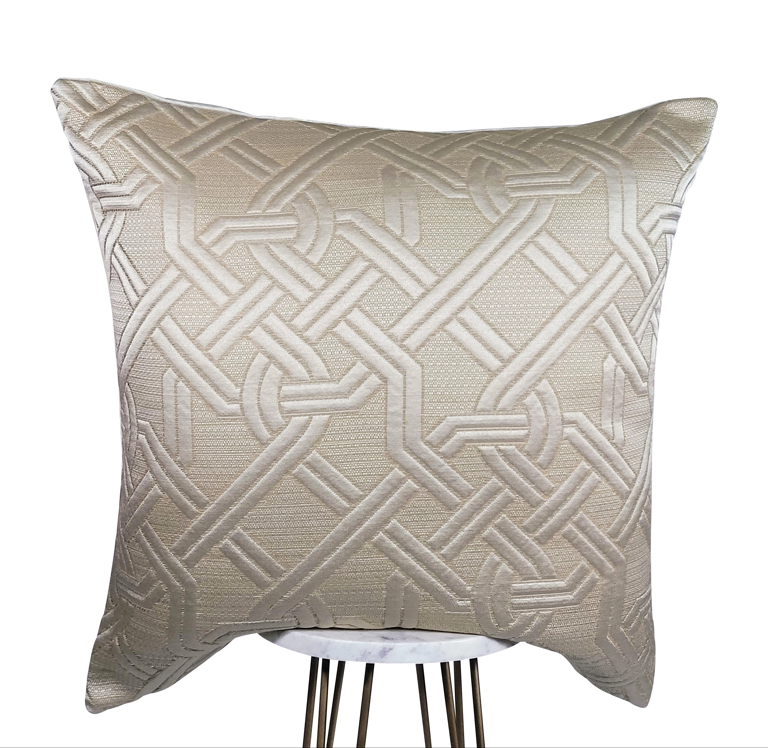 A square-shaped cream rope pillow with a geometric pattern of overlapping rope designs on a beige background.
