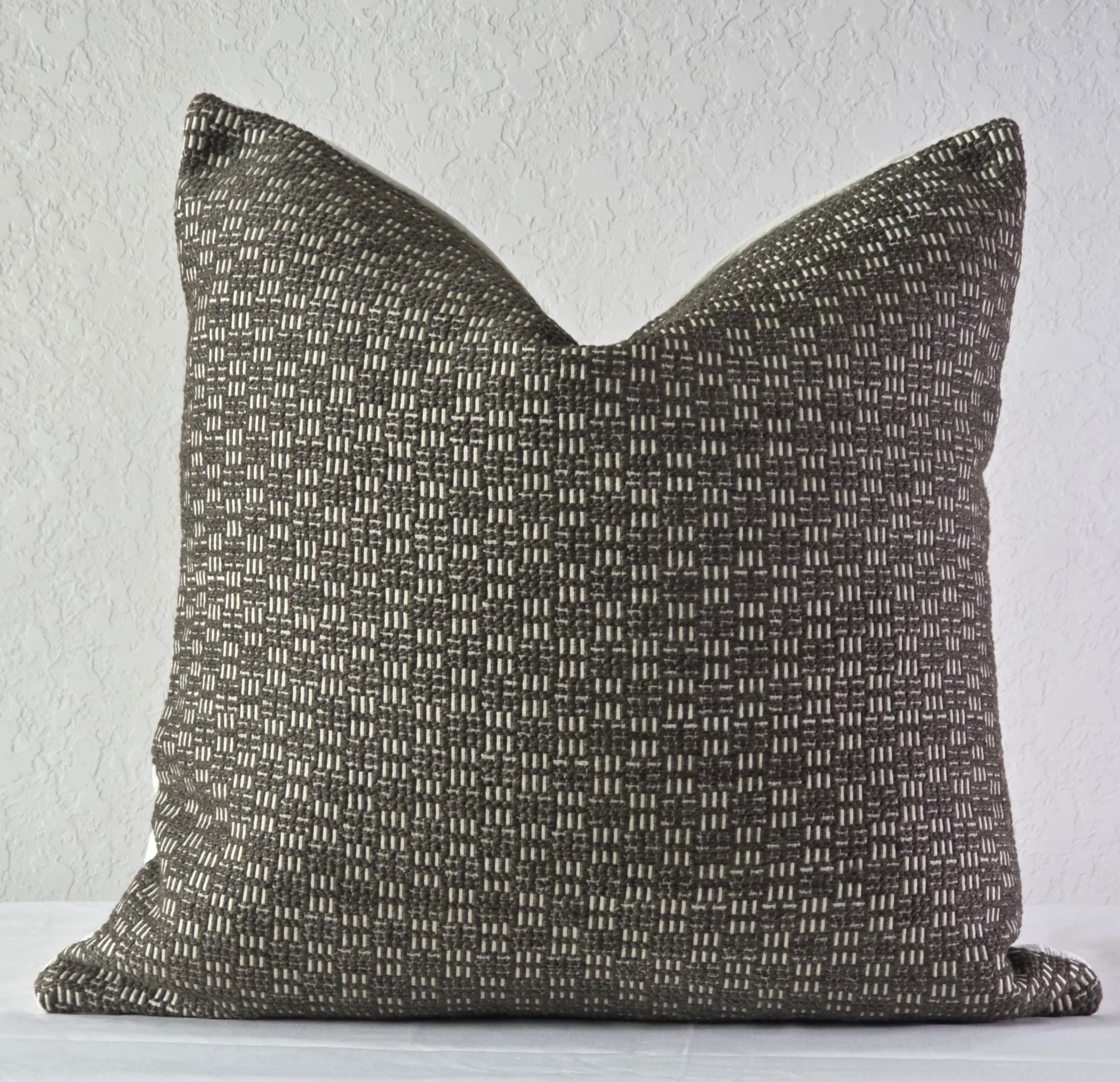 Textured brown pillow on a white surface with a light gray background