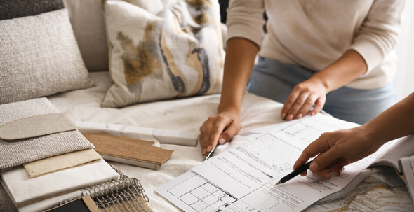Two people reviewing documents on a couch with color swatches and a pen.