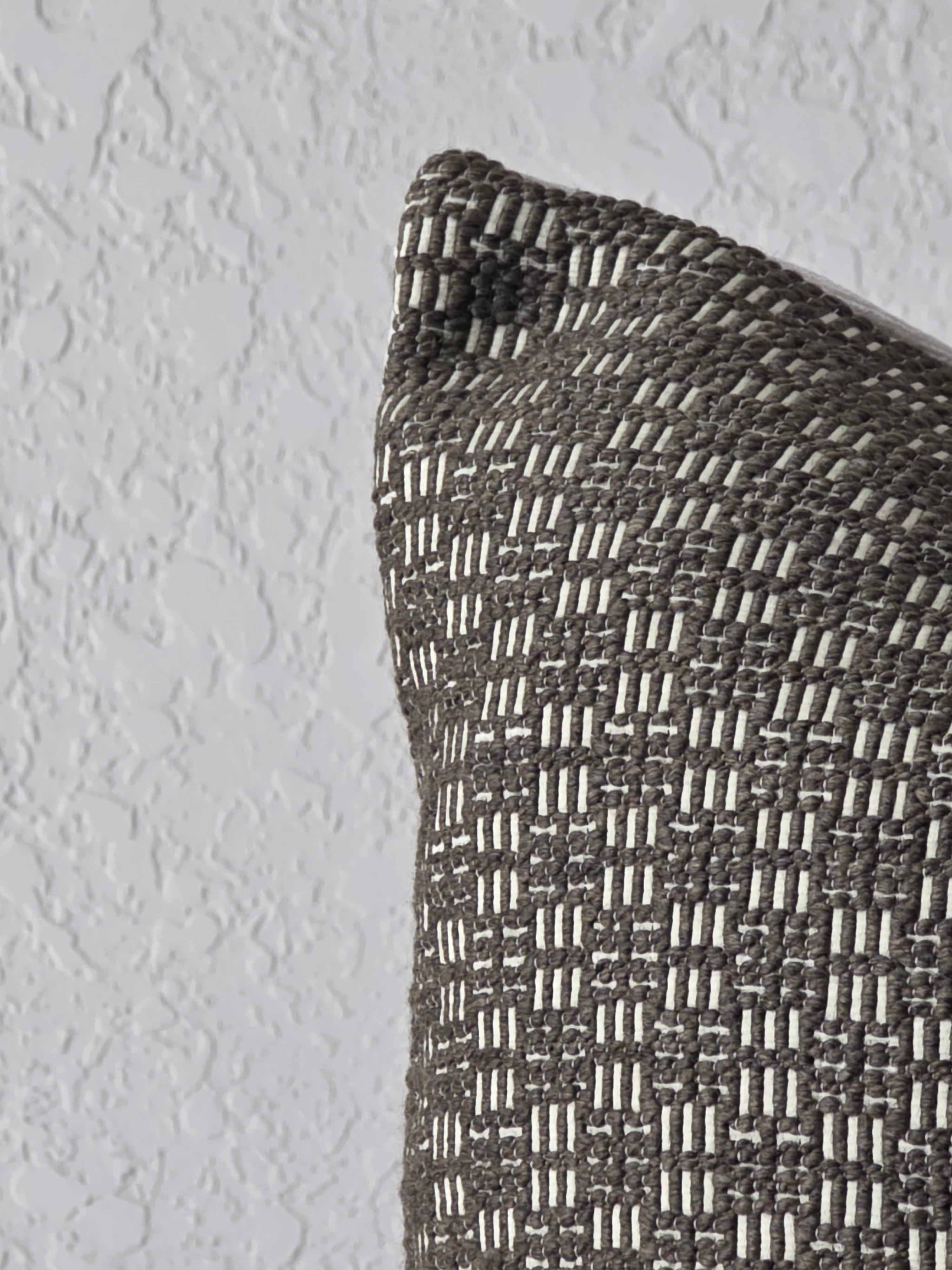Textured brown pillow against a light gray wall