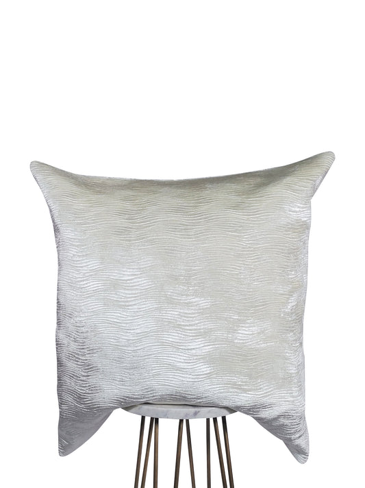 A square-shaped pillow with a shimmery wave texture in a neutral color scheme, displayed on a metallic stand.