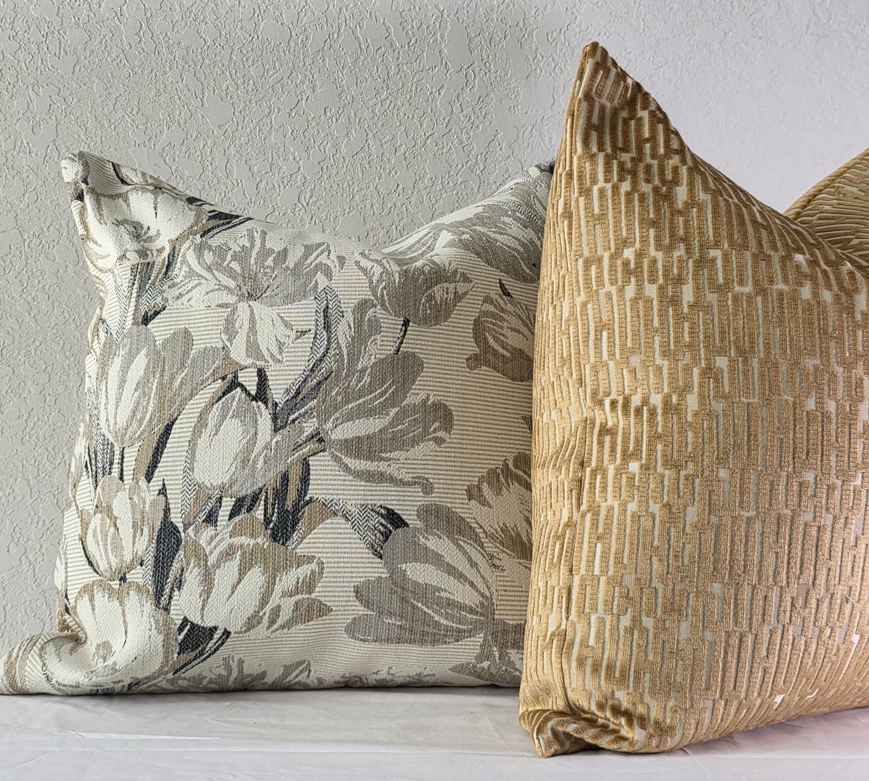 Two decorative pillows on a plain wall background