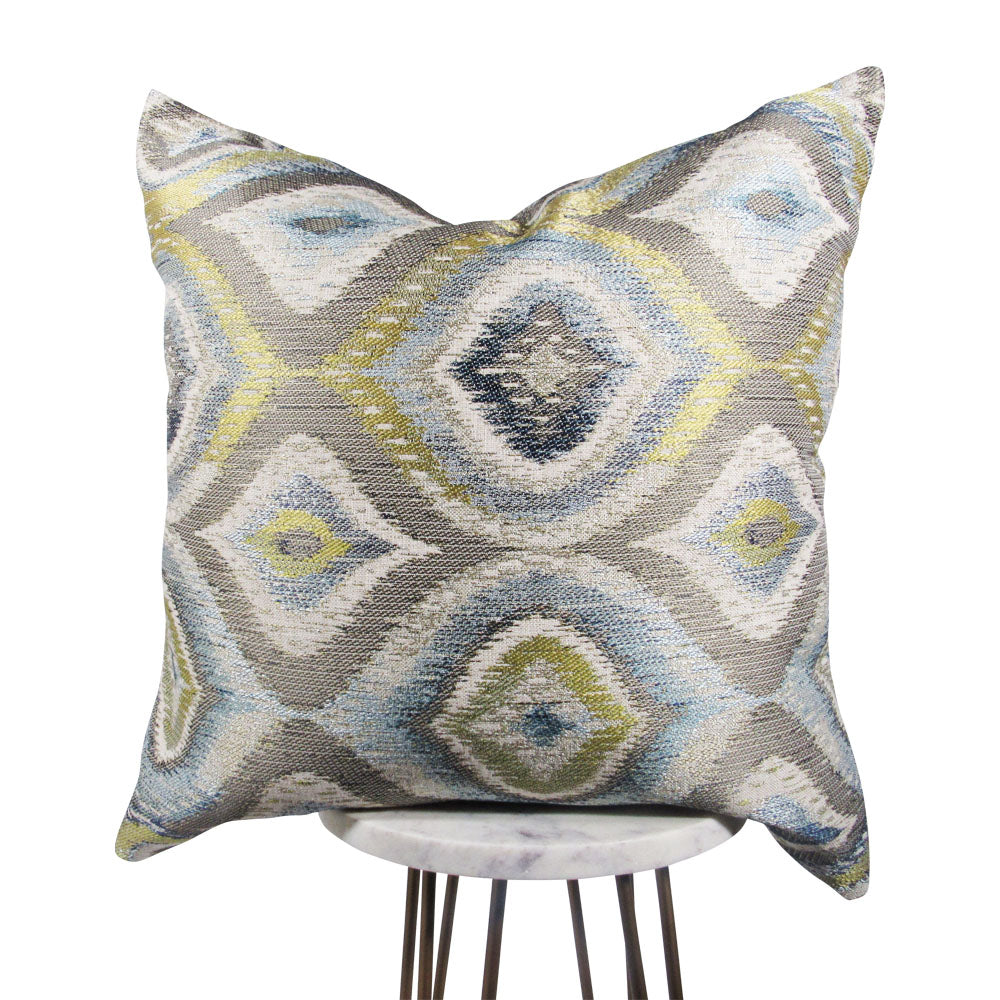 blue, green, gray and white 20x20 throw pillow with big designs, displayed on a small white table.