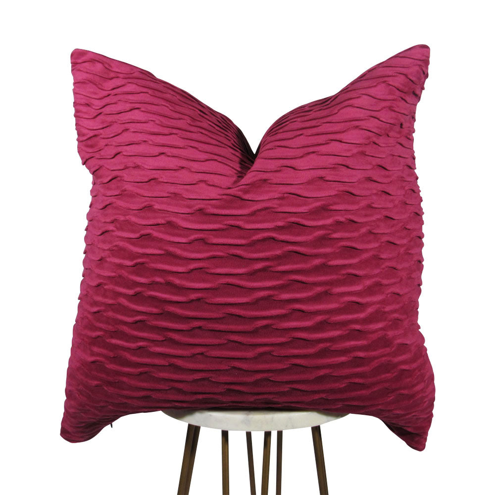 fuchsia 20x20 square throw pillow with wavy indented lines throughout, displayed on small white table.