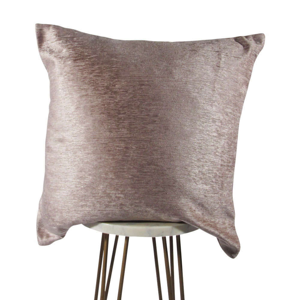 A pastel pink satin pillow cover on a chair with a hidden zipper closure.