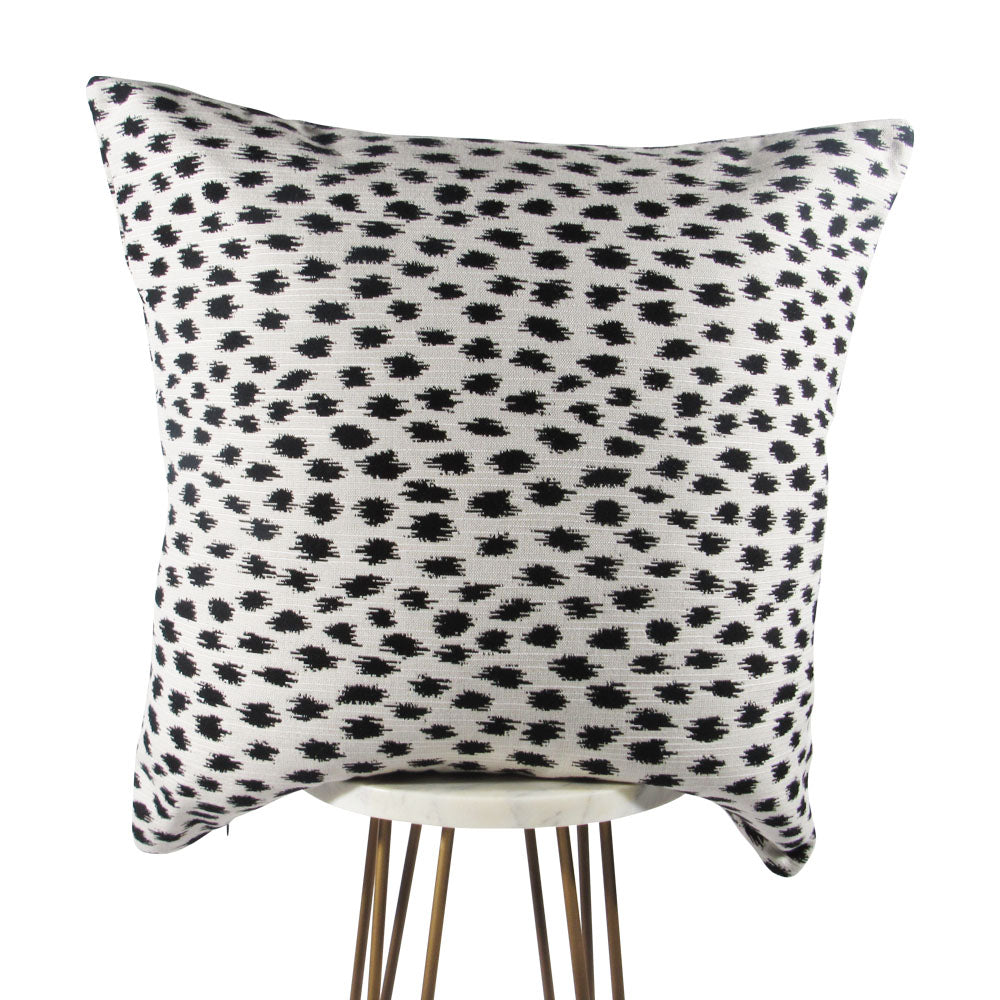 A square-shaped throw pillow with a black geometric pattern on a white background.