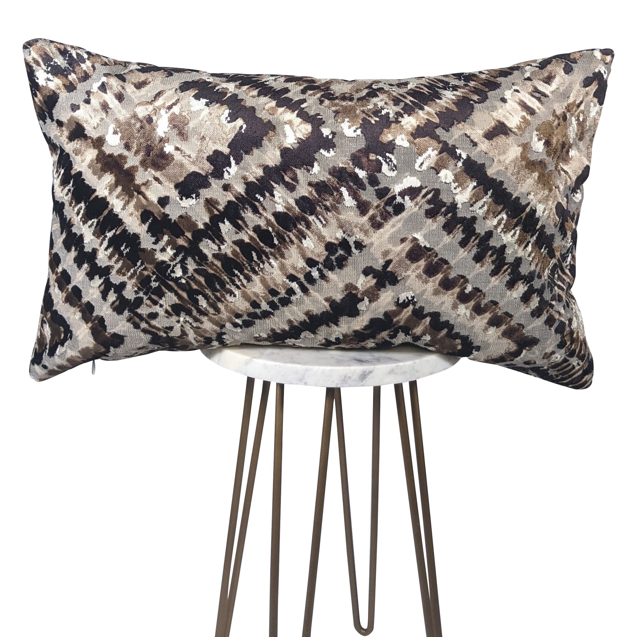 A rectangular throw pillow with an animal print in black, silver, and cream colors, displayed on a white stool.