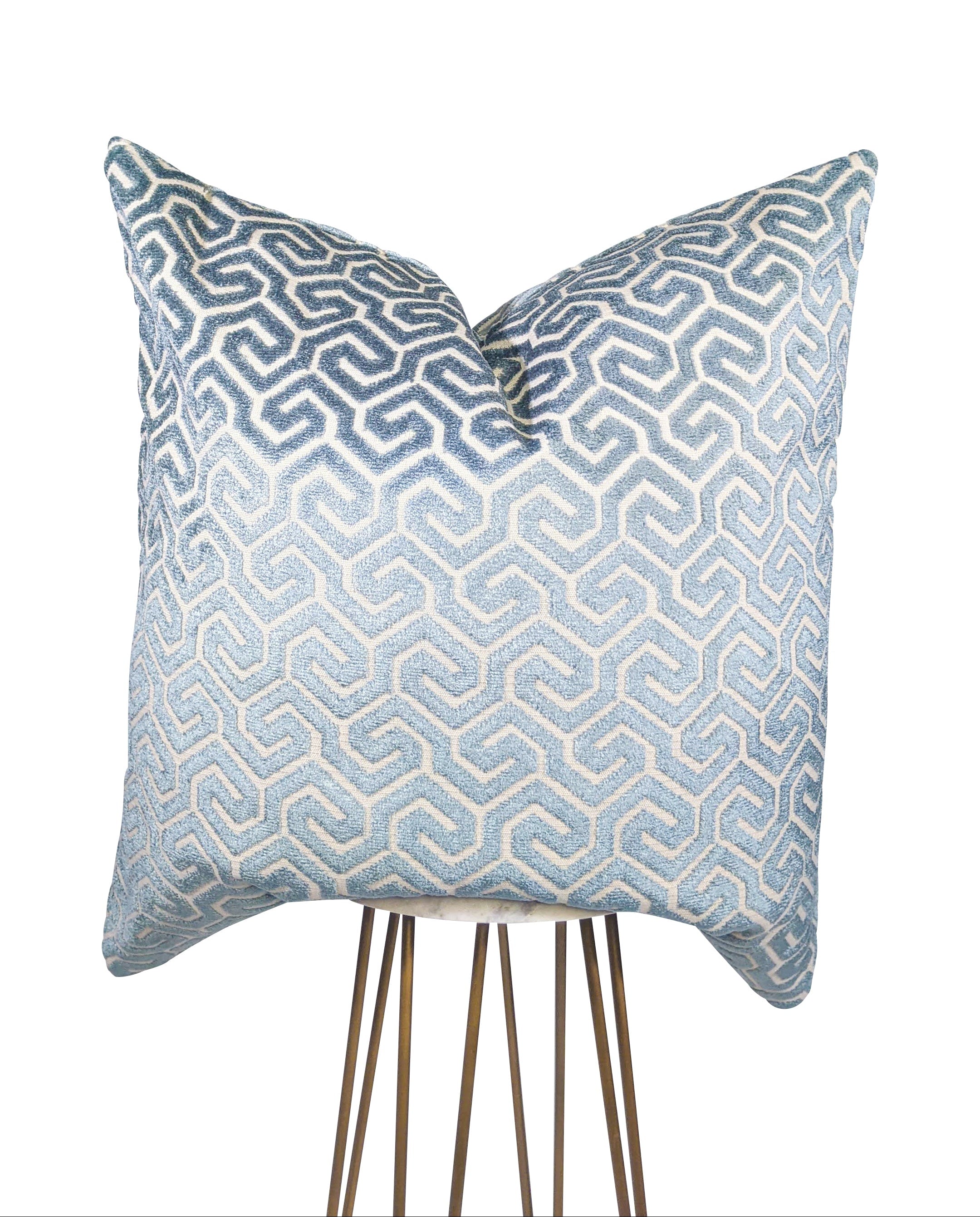 A cream and electric blue patterned pillow with a geometric design.