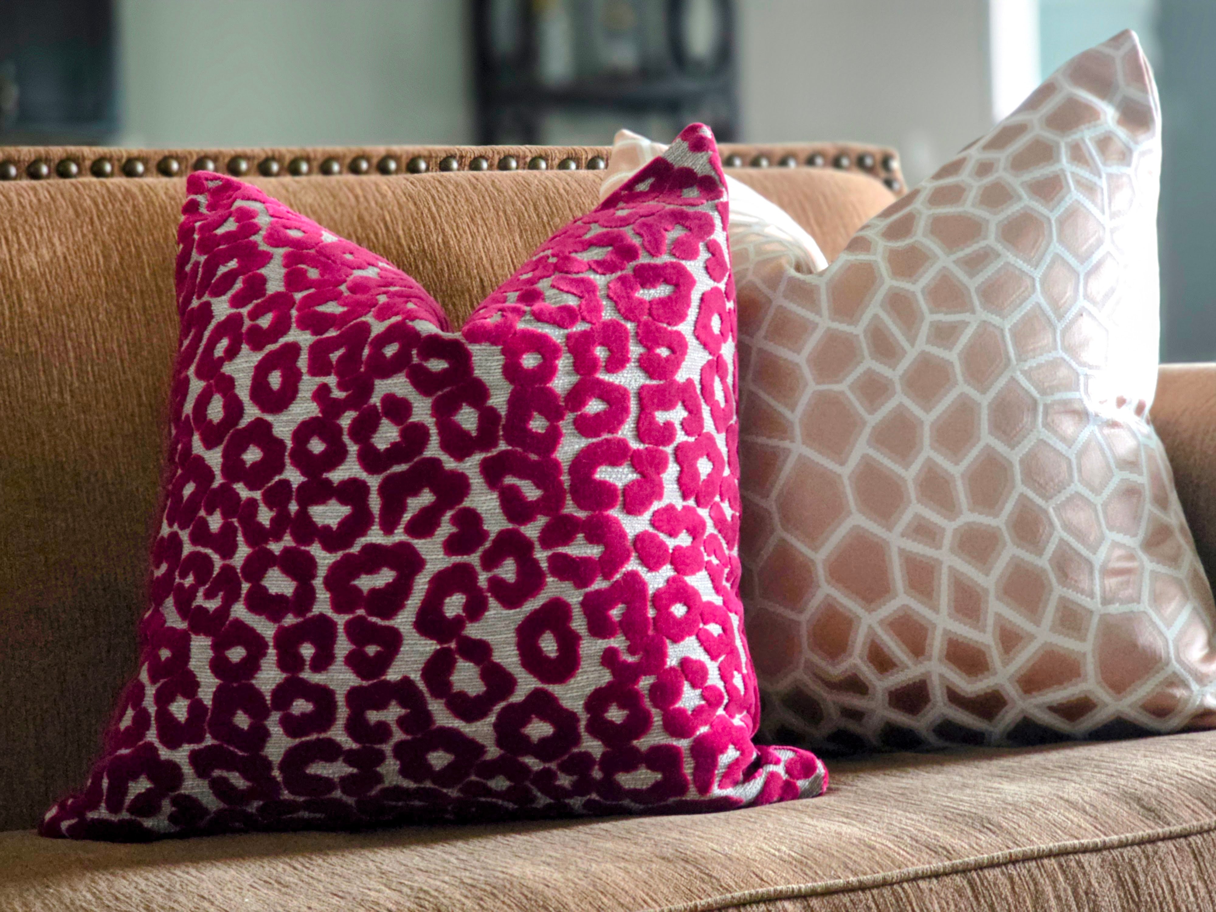 Pink leopard print pillow on a beige sofa with a white pillow.