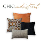 A set of four decorative throw pillows with a chic industrial design, including patterns and colors such as orange, black, and gray.