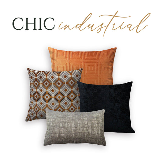 A set of four decorative throw pillows with a chic industrial design, including patterns and colors such as orange, black, and gray.