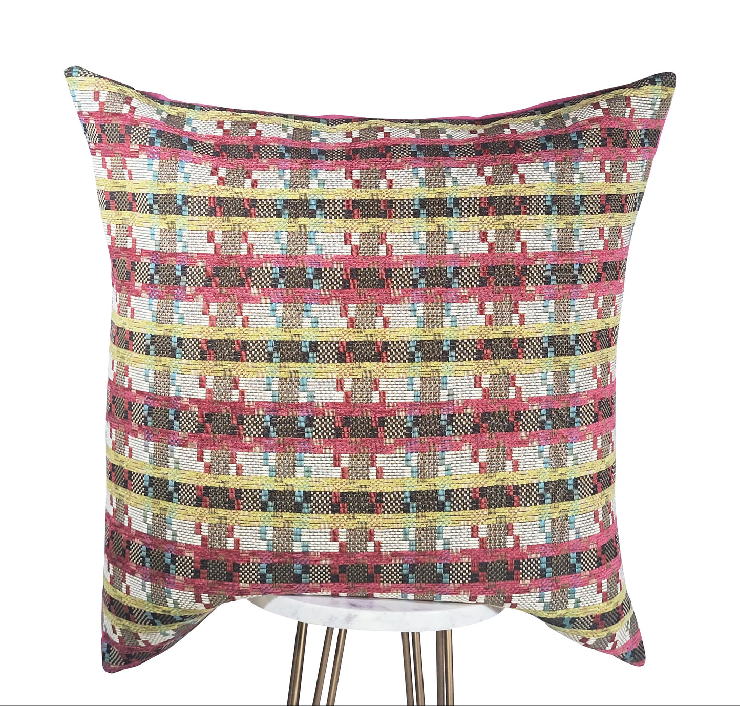 A square-shaped pink pillow with a geometric pattern featuring stripes in fuchsia, green, white, and blue colors.