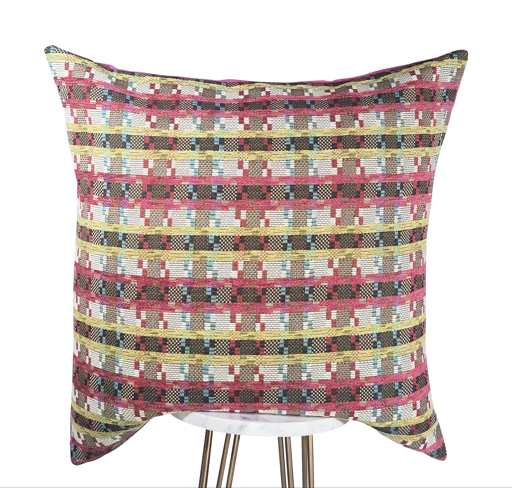 A square-shaped pink pillow with a geometric pattern featuring stripes in fuchsia, green, white, and blue colors.