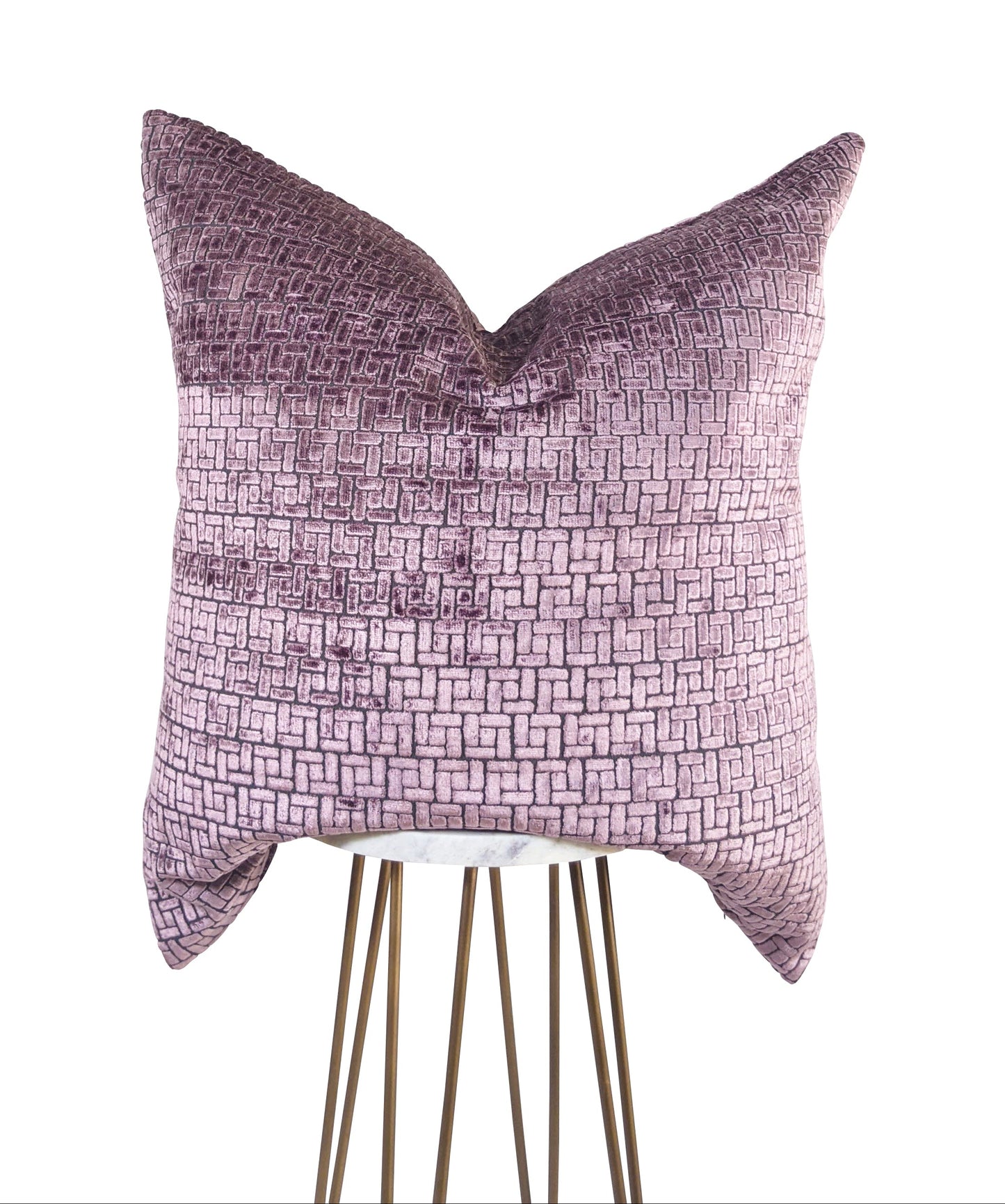 A rectangular-shaped mauve and gray geometric-patterned pillow with a velvet texture, displayed on a stand against a white background.