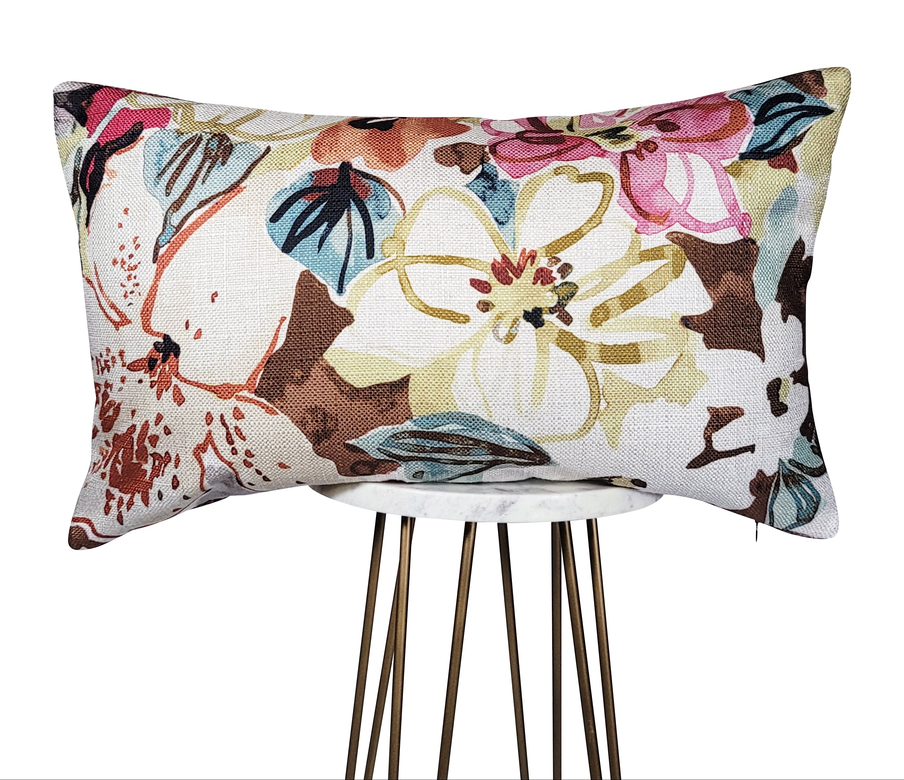 A square-shaped throw pillow with a floral pattern featuring burgundy, blue, and brown colors, showcased on a gold-colored stand.