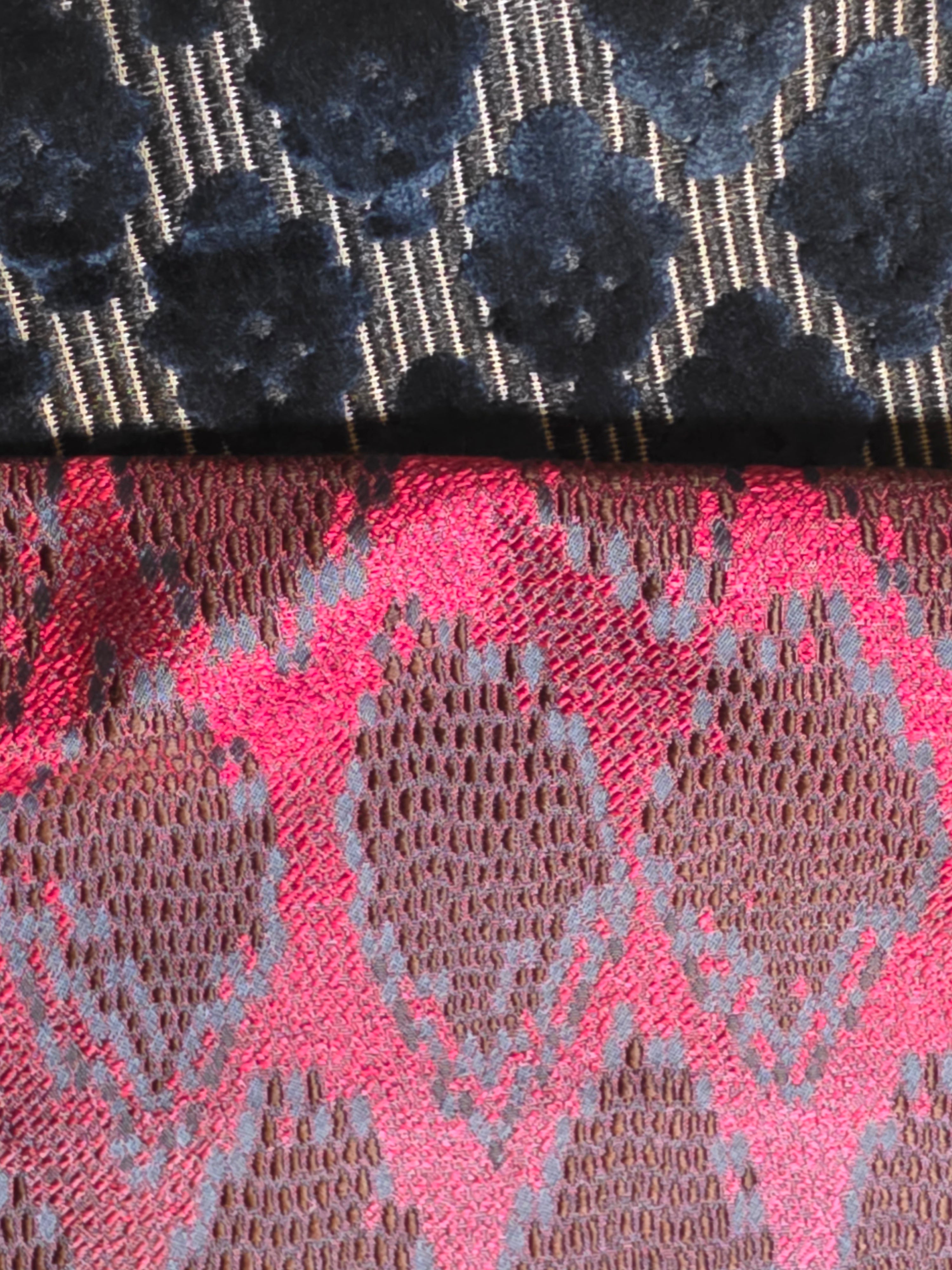 Close-up of two different fabric patterns, one black and one pink with a geometric design.