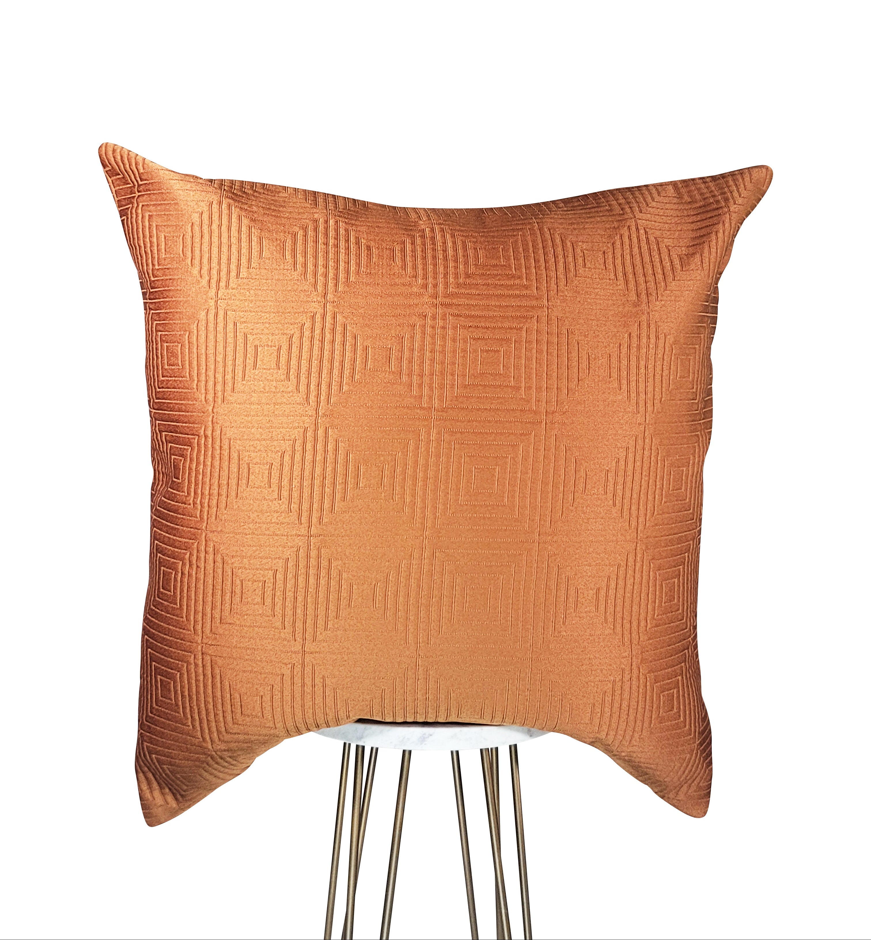 A rust orange square-patterned decorative pillow with a hidden zipper closure, placed on a chair.