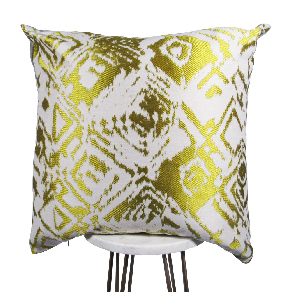 shiny gold square throw pillow with designs displayed on a small white table