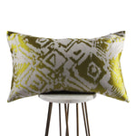 shiny gold lumbar throw pillow with designs displayed on a small white table