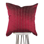 shiny fuchsia 20x20 square throw pillow with indented lines throughout, displayed on small white table. 