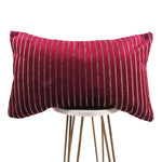 shiny fuchsia 13x21 rectangle throw pillow with indented lines throughout, displayed on small white table. 