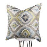 blue, green, gray and white 20x20 throw pillow with big designs, displayed on a small white table.