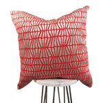 bright orange and silver 20x20 throw pillow with slanted lines, displayed on a small white table. 