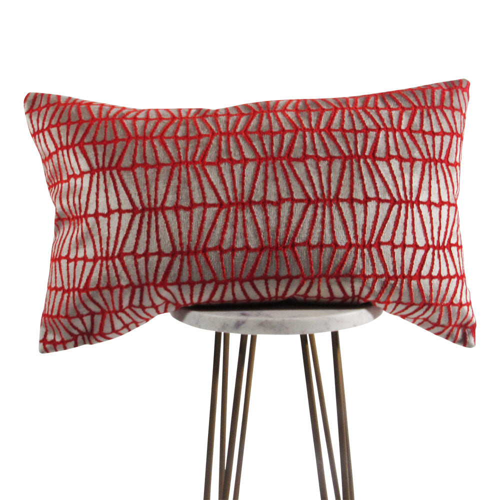 bright orange and silver 13x21 lumbar throw pillow with slanted lines, displayed on a small white table. 