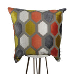 yellow, orange, gray and white 20x20 throw pillow with geometric shapes, displayed on small white table.