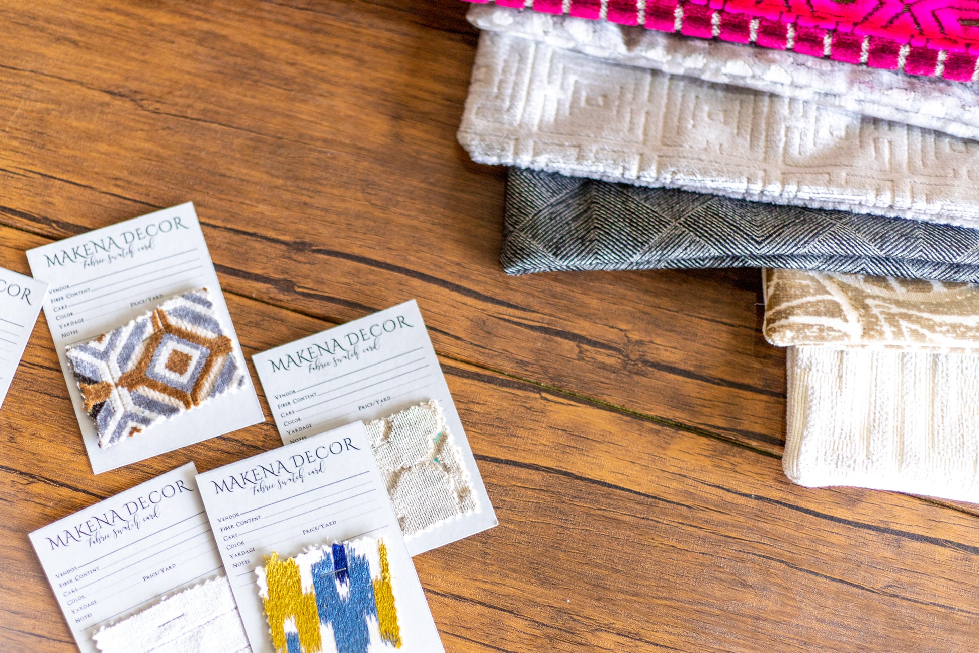Makena Decor fabric swatches with various  pillow covers on wood table 