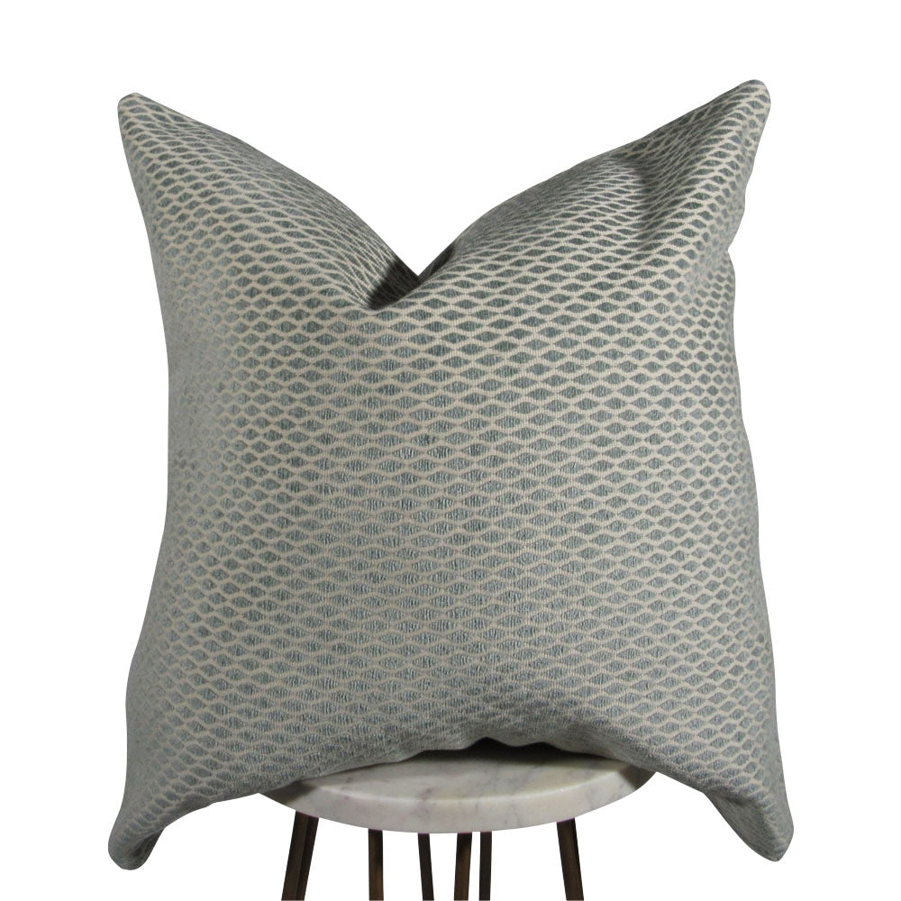 A square-shaped mint blue velvet pillow with a cream backdrop, featuring a geometric diamond pattern.