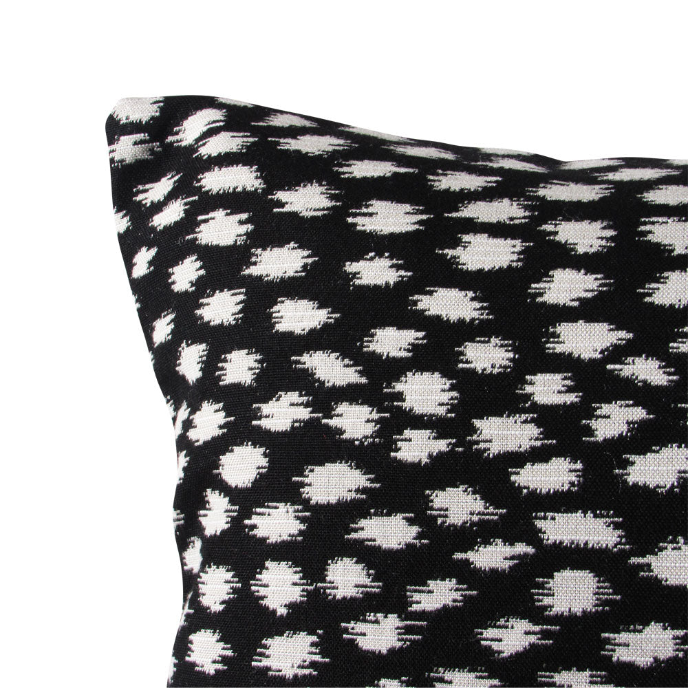 Close-up of black over white spot pattern on a decorative throw pillow cover.